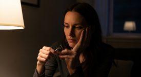 Người phụ nữ lo lắng khi cắt móng tay ban đêm, ánh sáng yếu.