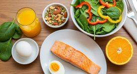 Mâm thực phẩm giàu dinh dưỡng bao gồm thịt đỏ, rau xanh, trứng, cá và hạt, tốt cho sức khỏe móng tay.