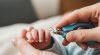 Bàn tay bé sơ sinh với móng tay dài được người lớn cắt tỉa cẩn thận bằng dụng cụ chuyên dụng